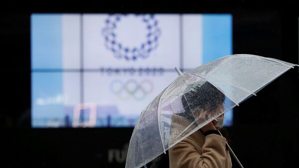 A passerby wearing a protective face mask walks past a display showing the logo of Tokyo 2020 Olympic Games that have been postponed to 2021 due to the coronavirus disease (COVID-19) outbreak, in Tokyo, Japan January 23, 2021. - 俄罗斯卫星通讯社