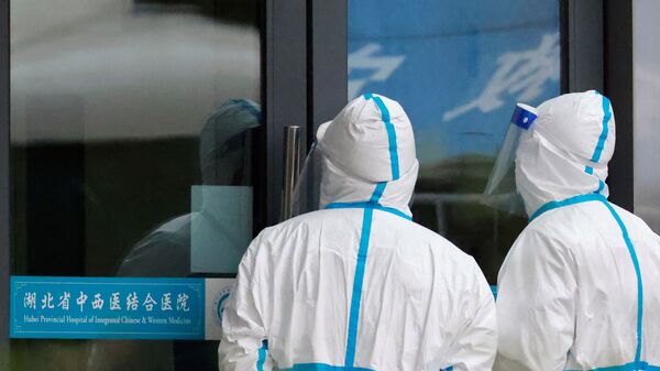Сотрудники в защитных костюмах стоят у больницы комплексной китайской и западной медицины провинции Хубэй, куда приезжают члены группы Всемирной организации здравоохранения (ВОЗ), которой поручено расследовать происхождение коронавирусной болезни (COVID-19), в Ухане, - 俄羅斯衛星通訊社