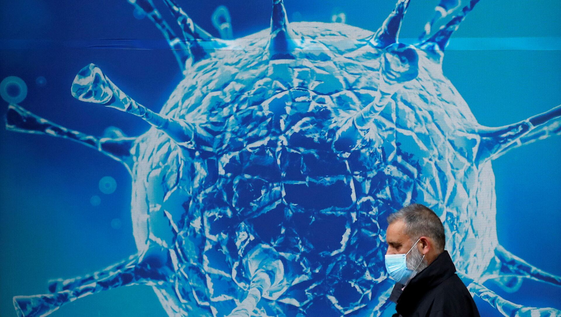 A man wearing a protective face mask walks past an illustration of a virus outside a regional science centre amid the coronavirus disease (COVID-19) outbreak, in Oldham, Britain 3 August 2020. - 俄罗斯卫星通讯社, 1920, 11.02.2021
