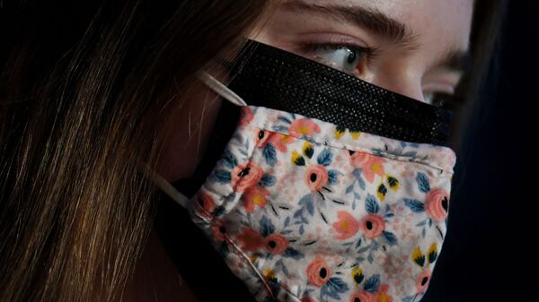 Девушка в двух лицевых масках, тканевой маске поверх хирургической маски, в Арлингтоне, штат Вирджиния, США - 俄羅斯衛星通訊社