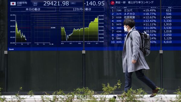 Мужчина на фоне экрана с индексами котировок японской фондовой биржи. 12 февраля 2021 - 俄罗斯卫星通讯社
