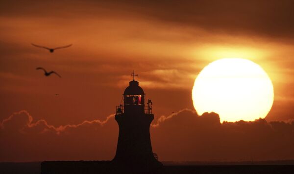 英格兰，南希尔兹灯塔上方升起的太阳。 - 俄罗斯卫星通讯社