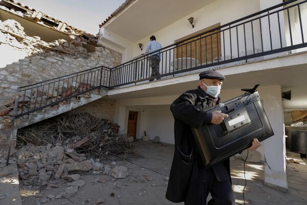 希臘發生地震後，一名男子帶著電視機在受損房屋外。 - 俄羅斯衛星通訊社