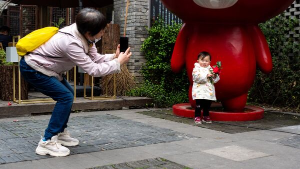 Женщина фотографирует ребёнка на улице в Ухане. - 俄罗斯卫星通讯社