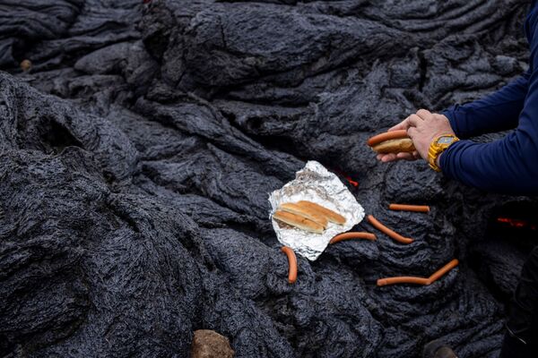 冰島火山爆發後，一名男子在雷克雅內斯半島的火山現場準備烤熱狗。 - 俄羅斯衛星通訊社