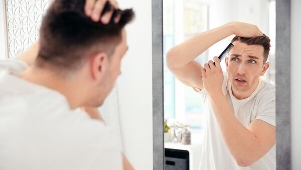 Мужчина рассматривает свои волосы в зеркале - 俄罗斯卫星通讯社