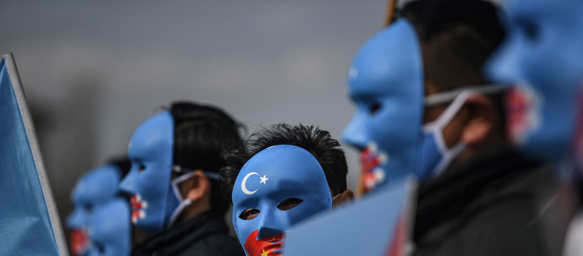 Demonstrators wearing a mask painted with the colours of the flag of East Turkestan - 俄羅斯衛星通訊社, 1920, 07.04.2021
