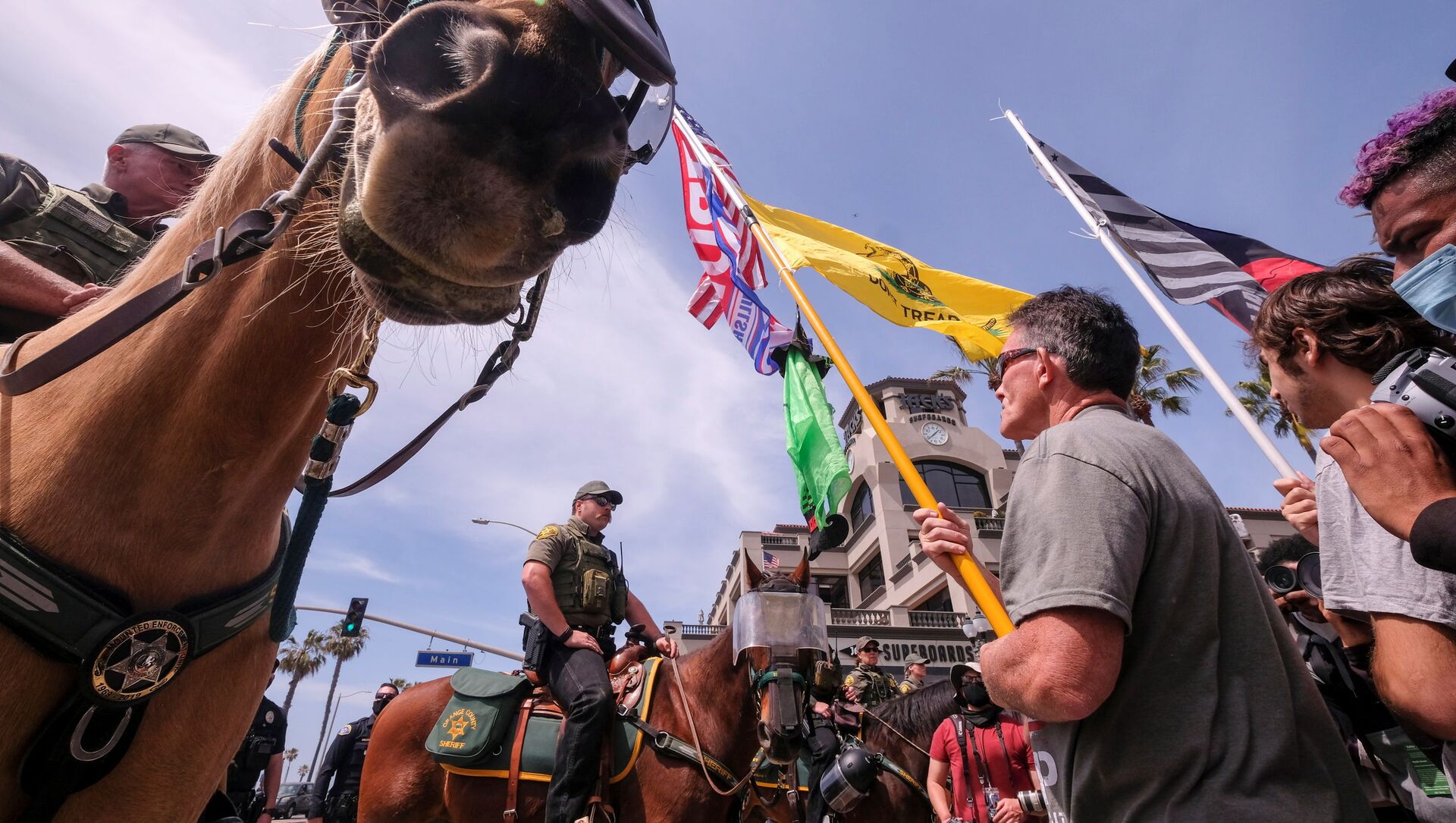 Demonstrators holding flags stand in front of a police line during a White Lives Matter protest in Huntington Beach, California, U.S. April 11, 2021 Demonstrators holding flags stand in front of a police line during a White Lives Matter protest in Huntington Beach, California, U.S. April 11, 2021 - 俄罗斯卫星通讯社, 1920, 12.04.2021