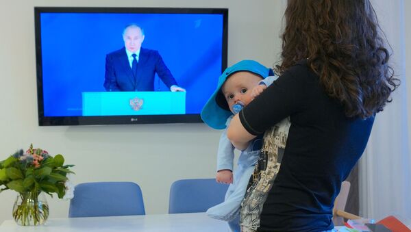 Женщина с ребенком смотрит обращение В. Путина к Федеральному собранию - 俄罗斯卫星通讯社