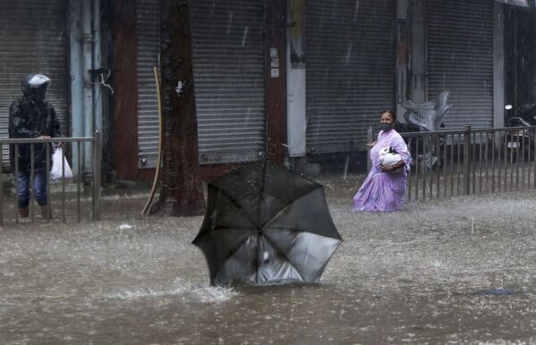 孟買，颶風肆虐時，一名女子走在被洪水淹沒的街道上。 - 俄羅斯衛星通訊社