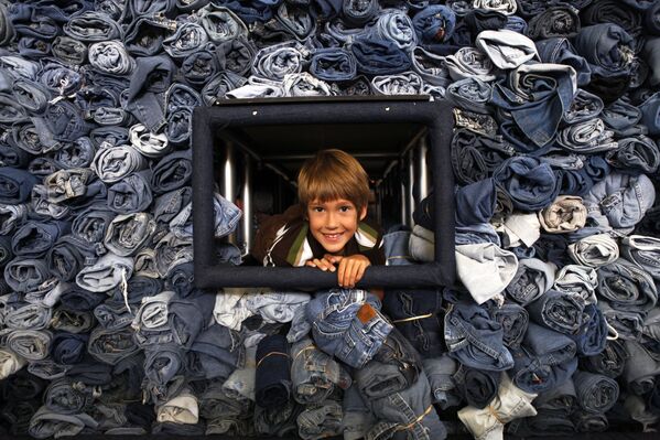2009年,俄亥俄州柯蒂斯市9岁男孩埃雷克·汉森(eric Hanson)从一个装有33088条牛仔裤的陈列柜里探出头来。这些牛仔裤是由国家地理儿童杂志(National Geographic Kids magazine)在华盛顿回收,用于制造房屋隔热材料。 2009年,俄亥俄州柯蒂斯市9岁男孩埃雷克·汉森(eric Hanson)从一个装有33088条牛仔裤的陈列柜里探出头来。这些牛仔裤是由国家地理儿童杂志(National Geographic Kids magazine)在华盛顿回收,用于制造房屋隔热材料。 - 俄罗斯卫星通讯社