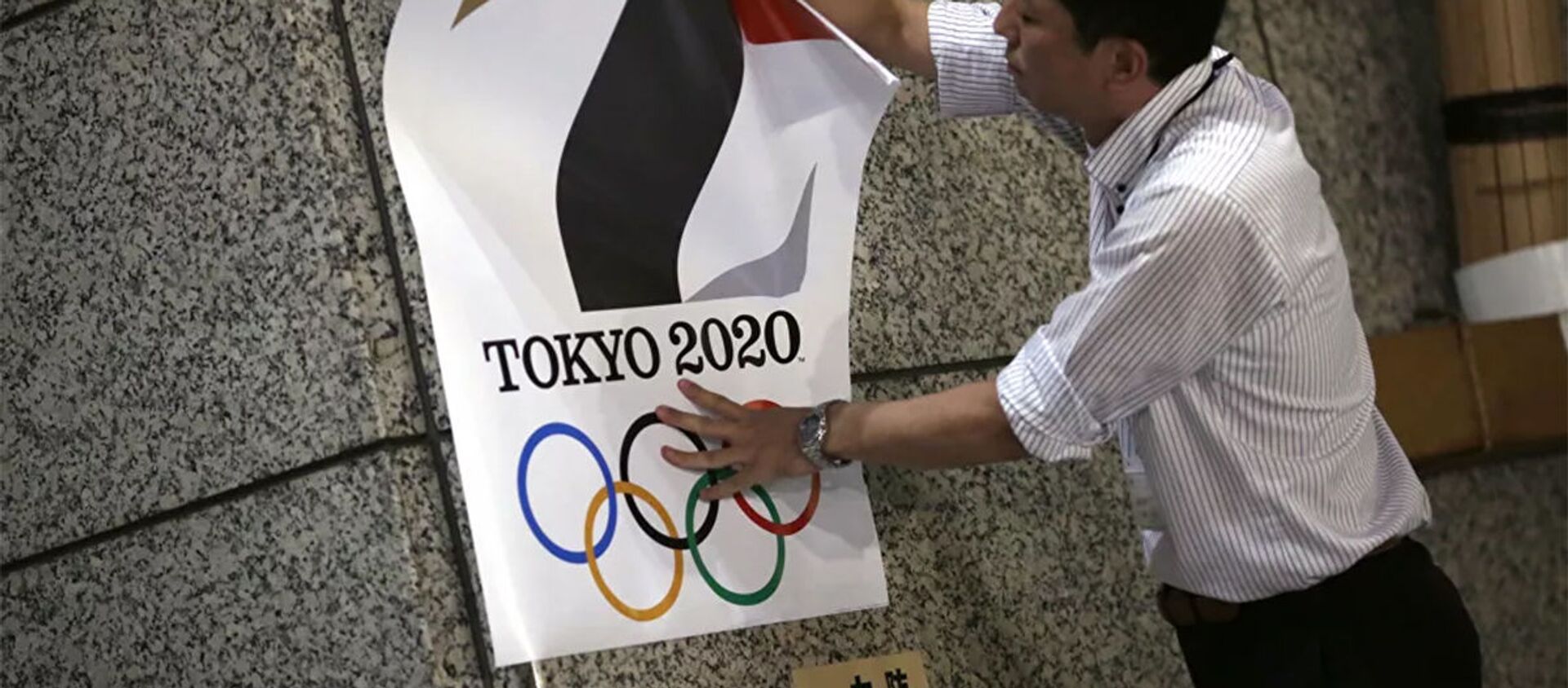 Мужчина вешает плакат с логотипом Олимпийских игр в Токио - 俄羅斯衛星通訊社, 1920, 25.05.2021