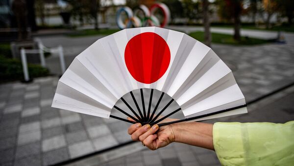 Веер с японским флагом напротив Олимпийских колец в Токио  - 俄罗斯卫星通讯社