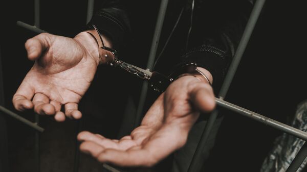 Мужчина в наручниках за решеткой в полицейском участке - 俄羅斯衛星通訊社