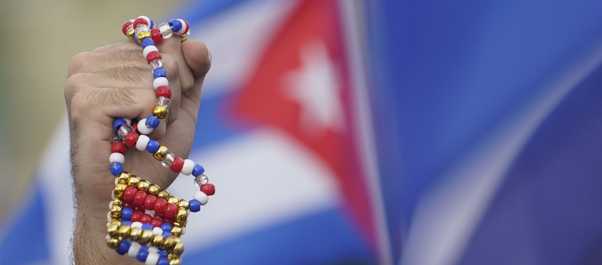 Демонстрант держит в руках ожерелье в Майями во время акции в поддержку антиправительственных выступлений на Кубе - 俄羅斯衛星通訊社, 1920, 15.07.2021