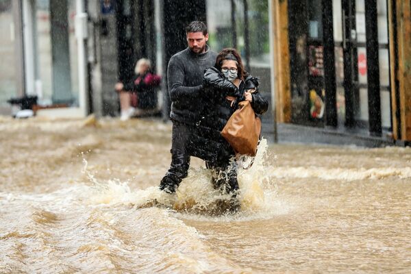 Мужчина помогает женщине пройтись по затопленной улице в городе Спа, Бельгия - 俄羅斯衛星通訊社