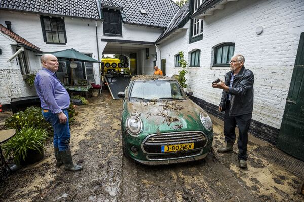 Жители стоят во дворе, покрытом грязью после сильного дождя в Херлене, Нидерланды - 俄罗斯卫星通讯社