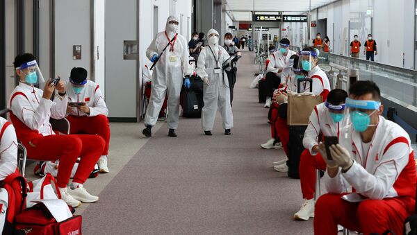 Сотрудники в защитных костюмах и сборная Китая в аэропорту Нарита  - 俄羅斯衛星通訊社