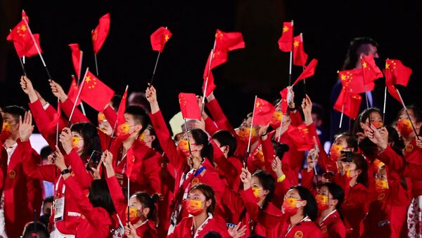 Члены китайской делегации машут флагами, входя на Олимпийский стадион во время церемонии открытия в Токио - 俄罗斯卫星通讯社