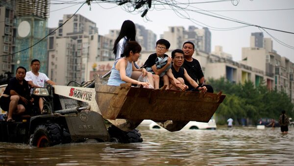 Люди едут на фронтальном погрузчике, пробираясь через паводковые воды после проливных дождей в Чжэнчжоу, провинция Хэнань, Китай - 俄罗斯卫星通讯社