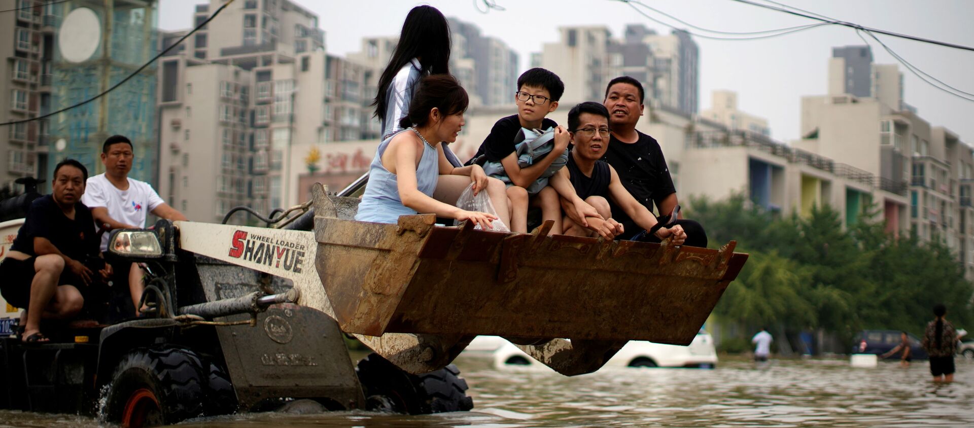 Люди едут на фронтальном погрузчике, пробираясь через паводковые воды после проливных дождей в Чжэнчжоу, провинция Хэнань, Китай - 俄羅斯衛星通訊社, 1920, 08.11.2021