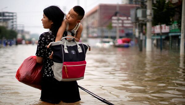 Женщина с ребенком и вещами пробирается через паводковые воды после проливного дождя в Чжэнчжоу, провинция Хэнань, Китай - 俄罗斯卫星通讯社