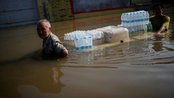 Жители деревни с бутылками с водой пробираются через паводковые воды после проливных дождей в деревне в Синьсяне, провинция Хэнань, Китай - 俄罗斯卫星通讯社