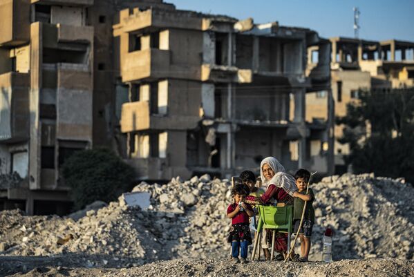 敘利亞拉卡，一名女子帶著孩子們在破損的房屋前玩耍。 - 俄羅斯衛星通訊社