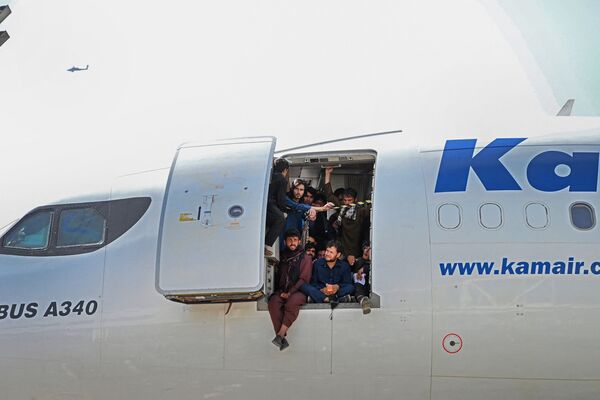 阿富汗人坐在喀布爾機場里一架飛機的機艙口。 - 俄羅斯衛星通訊社
