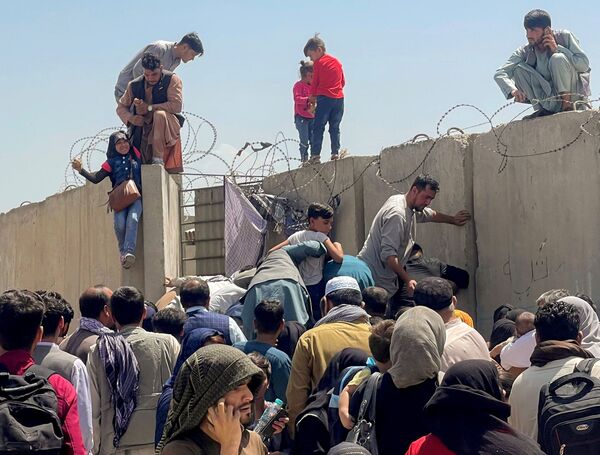 喀布爾機場附近，男子將一個女孩拉向圍牆頂上。 - 俄羅斯衛星通訊社
