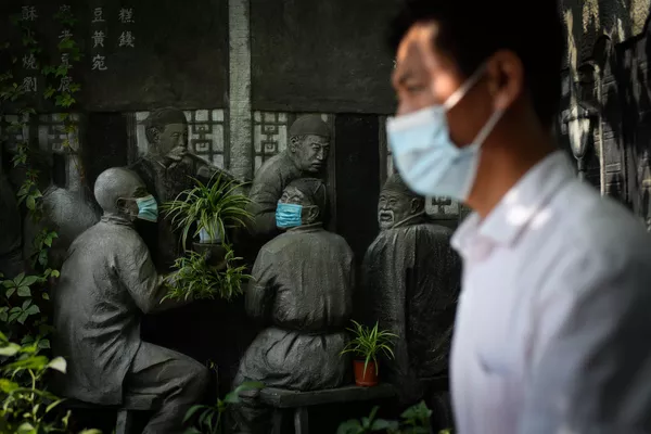 一位佩戴口罩的北京市民路過一處雕塑。 一位佩戴口罩的北京市民路過一處雕塑。 - 俄羅斯衛星通訊社