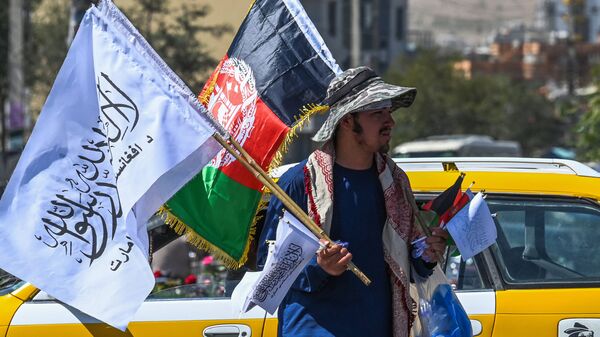 Мужчина продает государственный флаг Афганистана и флаг Талибана на улице Кабула - 俄羅斯衛星通訊社