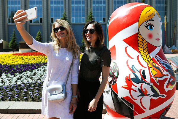 萨马拉河岸边，姑娘们在艺术家为2018年俄罗斯世界杯绘制的套娃旁边拍照留念。 - 俄罗斯卫星通讯社