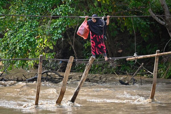 一女子通過一座被洪水衝垮的橋，印尼南蘇拉威西省 - 俄羅斯衛星通訊社