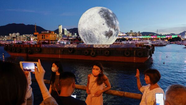 People pose in front of a giant moon-shaped balloon ahead of Mid-Autumn Festival, in Hong Kong, China September 20, 2021.  - 俄羅斯衛星通訊社