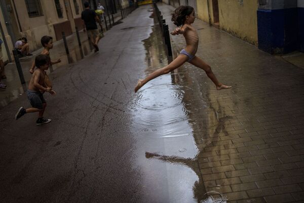 孩子们在雨中跳进水坑里，西班牙巴塞罗那  - 俄罗斯卫星通讯社