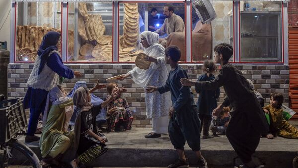 Женщина раздает хлеб нуждающимся детям перед пекарней в Кабуле - 俄罗斯卫星通讯社