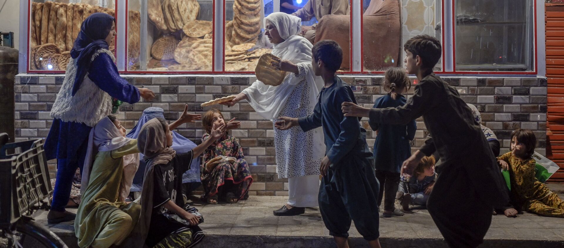 Женщина раздает хлеб нуждающимся детям перед пекарней в Кабуле - 俄罗斯卫星通讯社, 1920, 27.09.2021