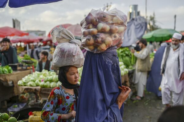 一個身穿罩衫的女子頭頂一袋洋蔥走在喀布爾的市場里。 - 俄羅斯衛星通訊社