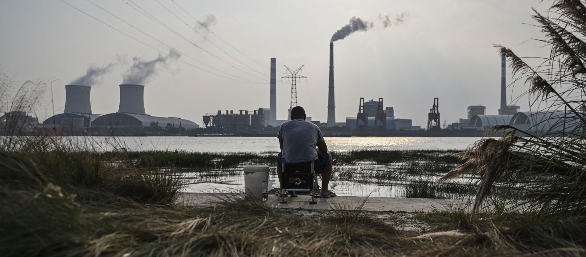 An angler is seen fishing along the Huangpu river across the Wujing Coal-Electricity Power Station in Shanghai - 俄羅斯衛星通訊社, 1920, 06.10.2021