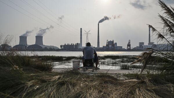 An angler is seen fishing along the Huangpu river across the Wujing Coal-Electricity Power Station in Shanghai - 俄羅斯衛星通訊社