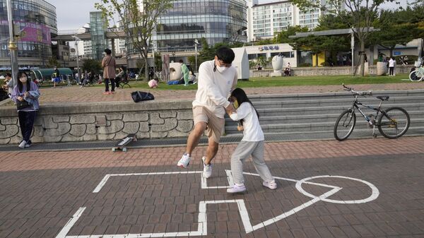 Сон Кван Чже и его дочь Чжэ Ин играют в оригинальную «Игру в кальмара» в парке в Кояне, Южная Корея - 俄罗斯卫星通讯社