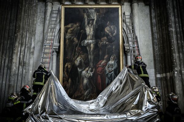 法国消防队员在波尔多圣安德烈教堂进行艺术品防火演习。图为消防队员为画作遮盖防火布。 - 俄罗斯卫星通讯社