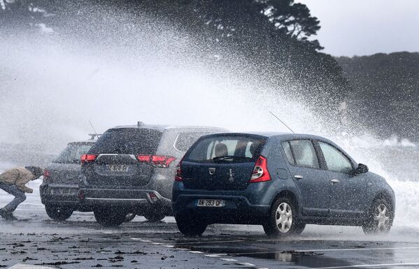法國，當海浪襲擊勒雷萊克-凱魯翁的海岸時，一名男子躲在汽車後面。 - 俄羅斯衛星通訊社