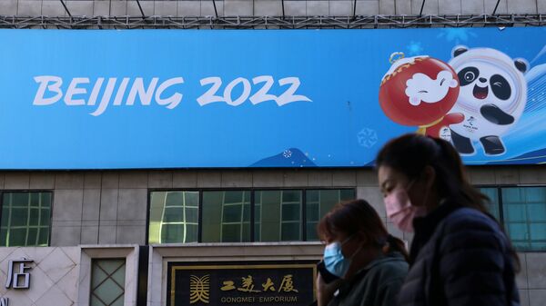 Люди напротив баннера Олимпийских игр в Пекине в Китае  - 俄羅斯衛星通訊社