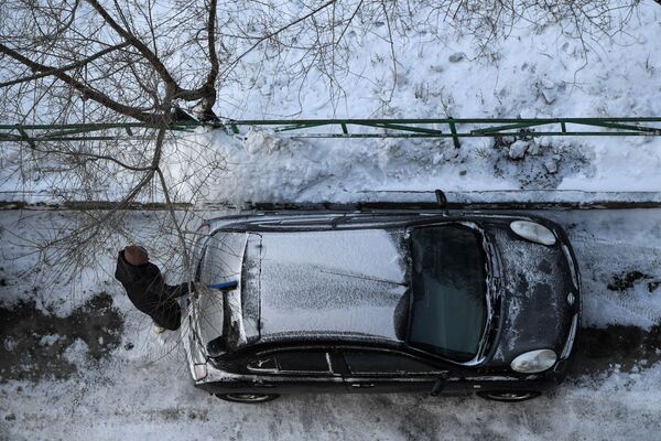 一女子清理车上的积雪  - 俄罗斯卫星通讯社