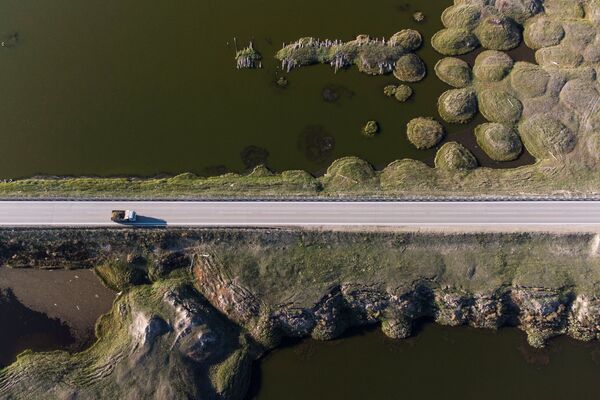 俄罗斯萨哈共和国，一辆卡车沿着科雷马联邦公路行驶，穿过丘拉普恰村附近因永久冻土融化而变形的土地。 - 俄罗斯卫星通讯社