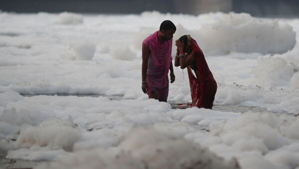 Индуистская пара поклоняется богу Солнца, стоя среди пены, покрывающей загрязненную реку Ямуна, во время индуистского религиозного фестиваля Чхат Пуджа в Нью-Дели - 俄羅斯衛星通訊社
