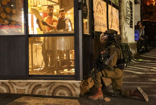 希伯倫市一麵包房廚師注視著正在驅趕巴勒斯坦人的以色列士兵。 - 俄羅斯衛星通訊社