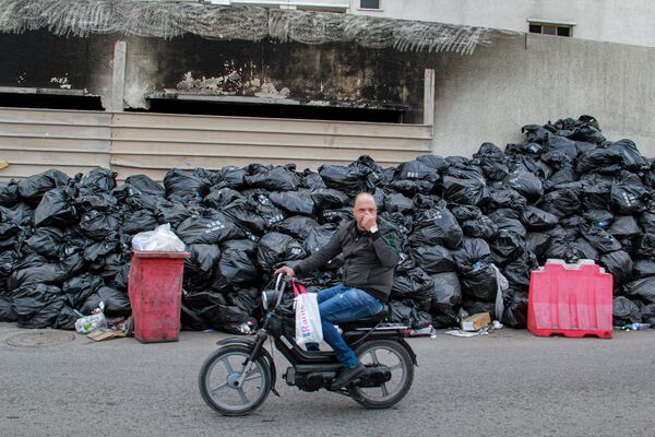 突尼斯斯法克斯市居民手捏鼻子走過垃圾袋。 - 俄羅斯衛星通訊社